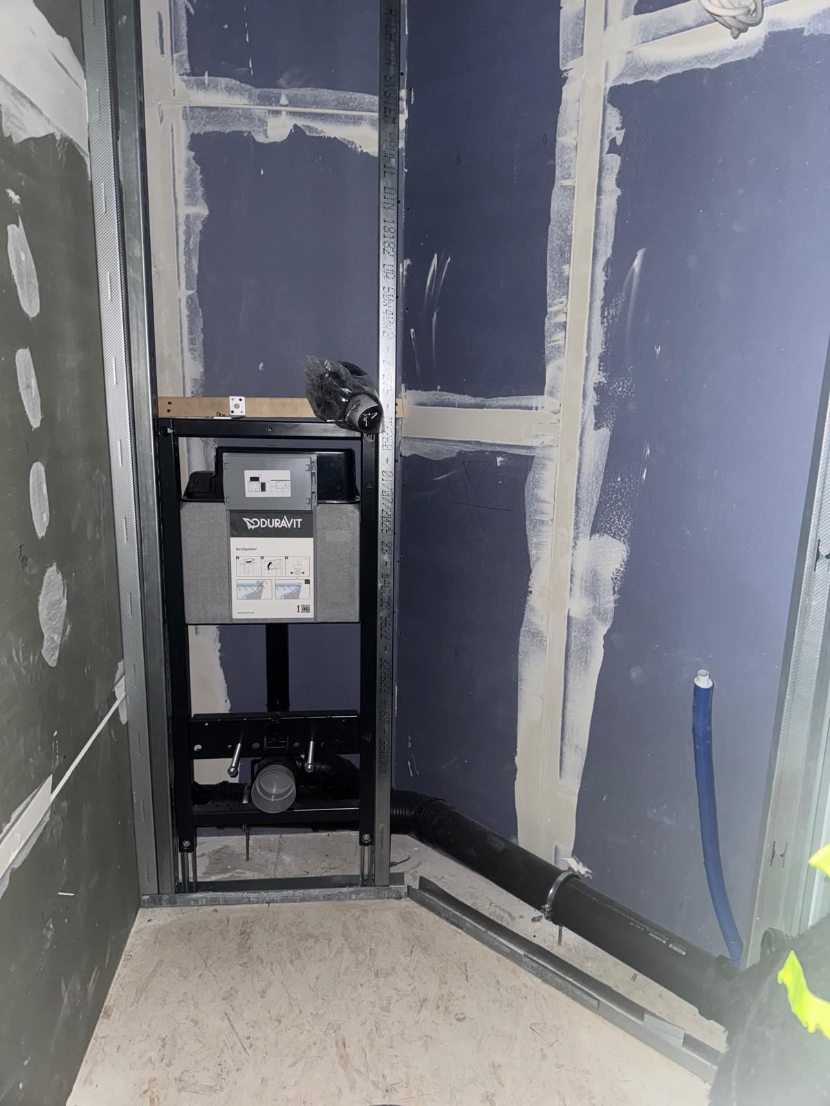 Sanitärvorwand mit WC-Element und sichtbaren Rohrleitungen im Ausbau