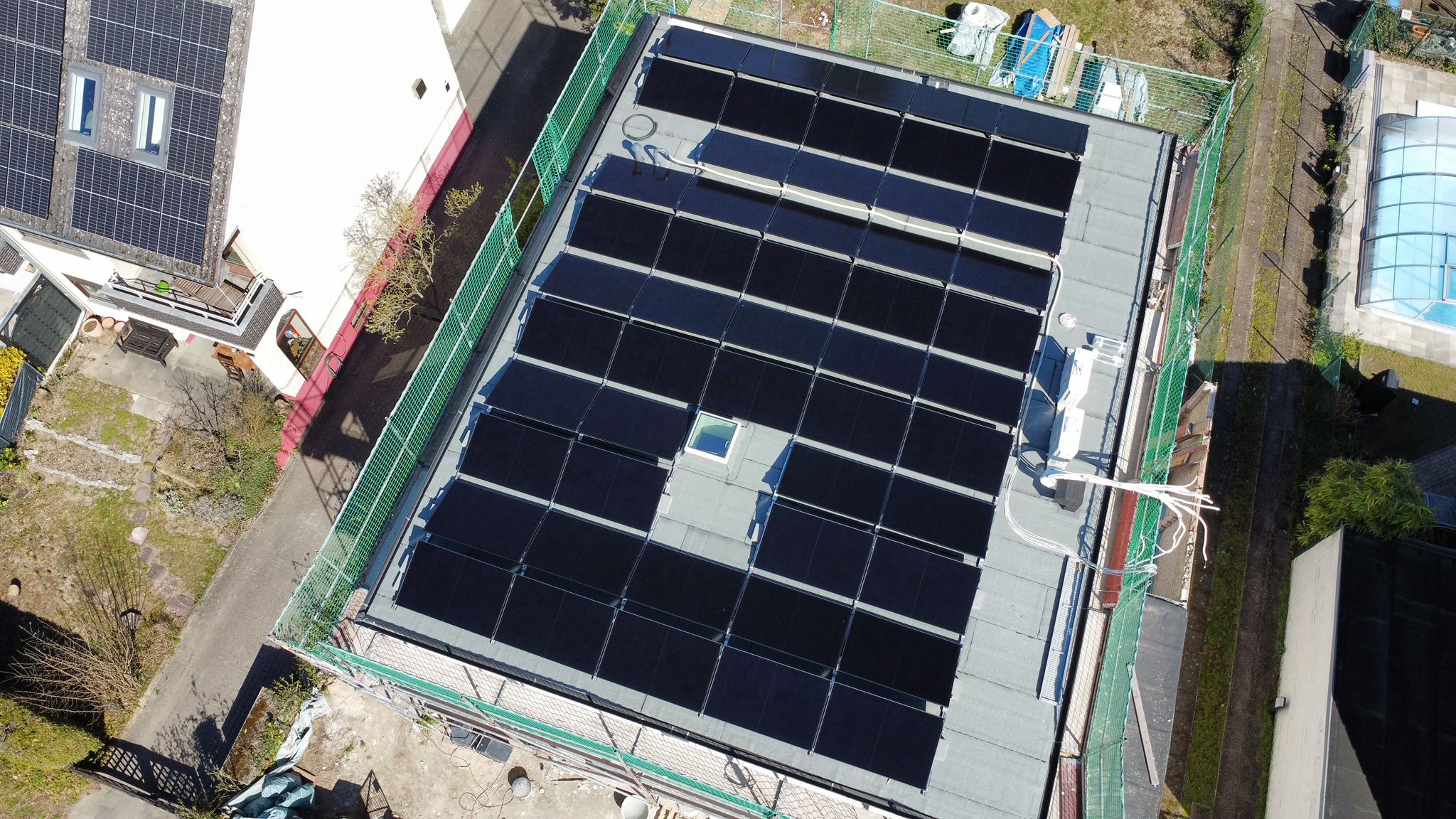 Drohnenblick auf die Photovoltaikmodule und das Flachdach des Einfamilienhauses