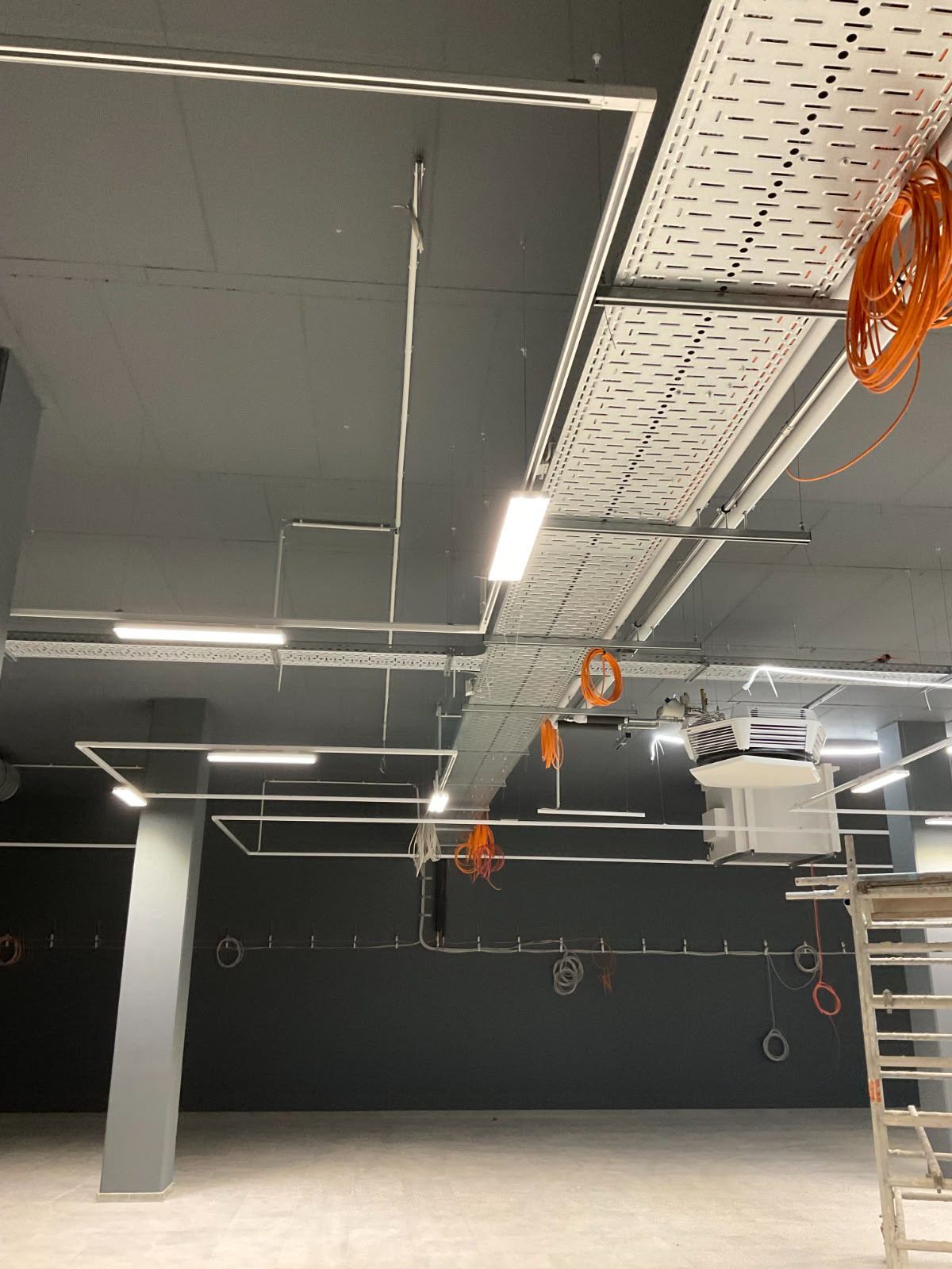 Offene Deckeninstallation mit Leuchten und Kabelwegen