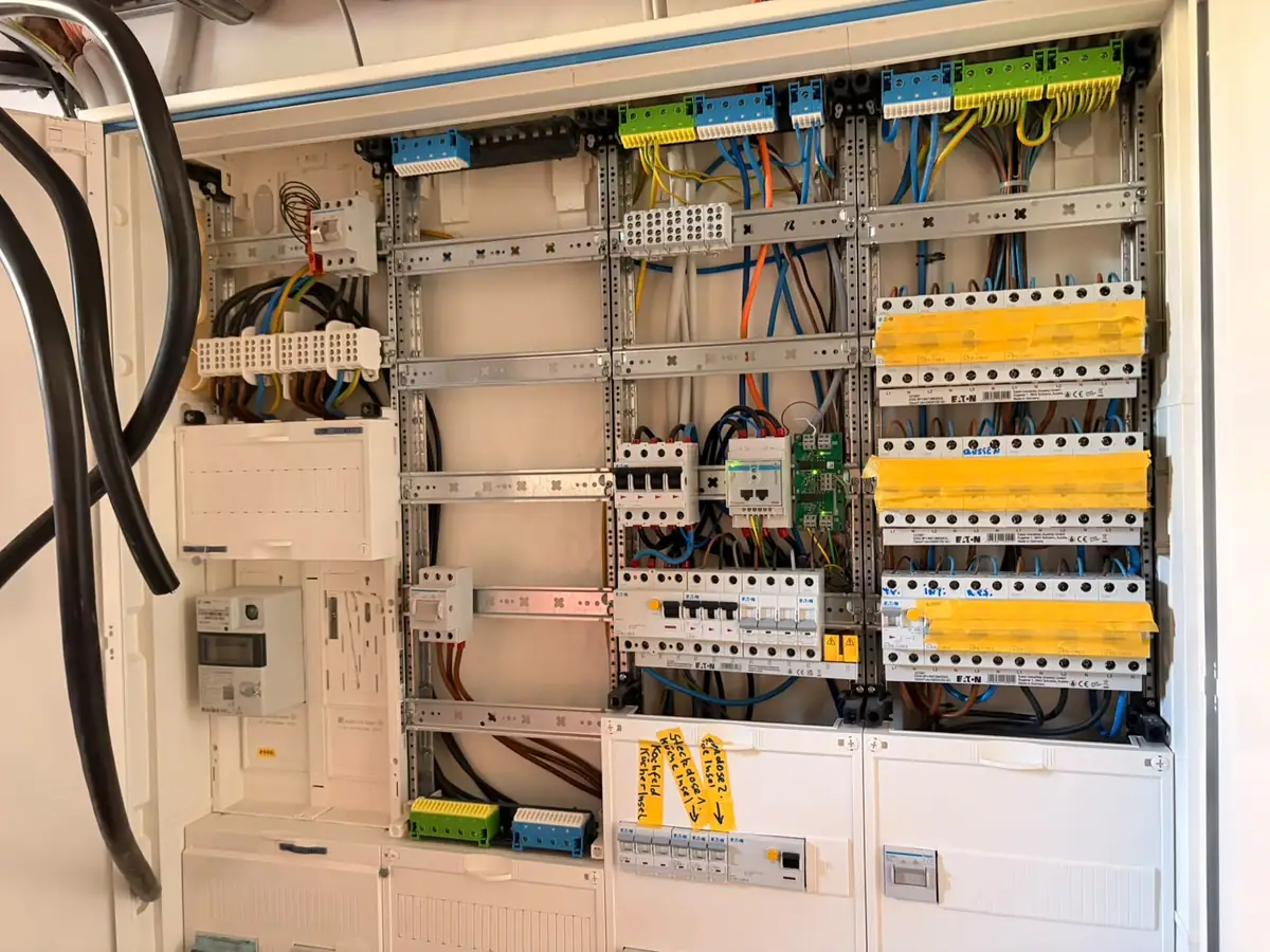 Geöffnete elektrische Verteilung mit Zähler und angeschlossenen Leitungen